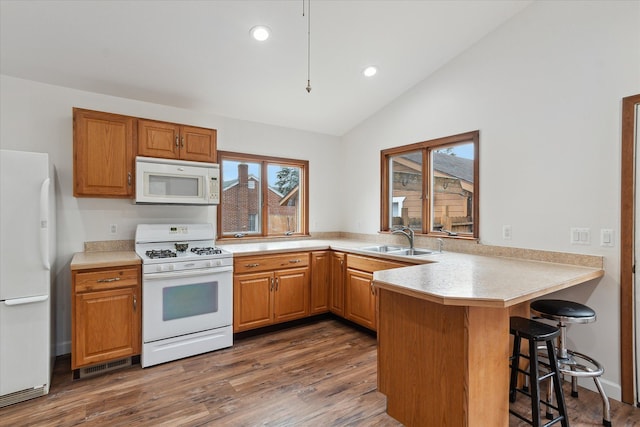 kitchen featuring plenty of natural light, white appliances, lofted ceiling, and a sink