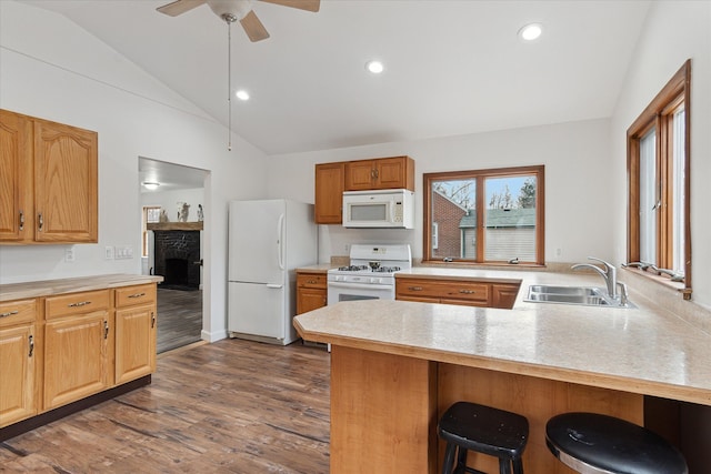 kitchen with a sink, dark wood finished floors, white appliances, light countertops, and vaulted ceiling