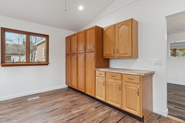 kitchen featuring visible vents, baseboards, light countertops, lofted ceiling, and wood finished floors