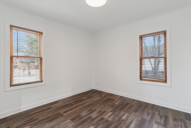 unfurnished room with dark wood-style floors, plenty of natural light, baseboards, and visible vents