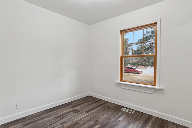 empty room with dark wood finished floors, baseboards, and visible vents