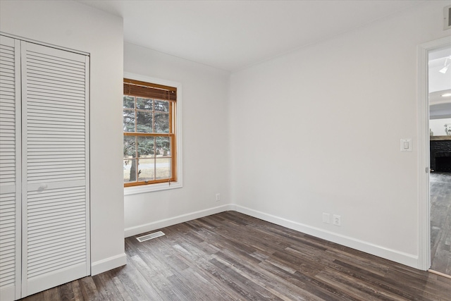 unfurnished bedroom featuring dark wood-style floors, visible vents, a closet, and baseboards