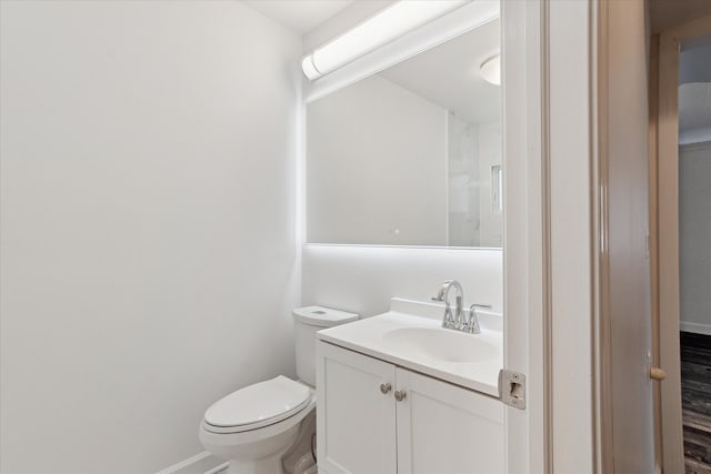 bathroom with toilet, vanity, and baseboards