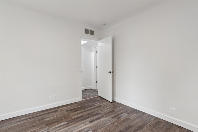 spare room featuring visible vents, baseboards, and dark wood-style flooring