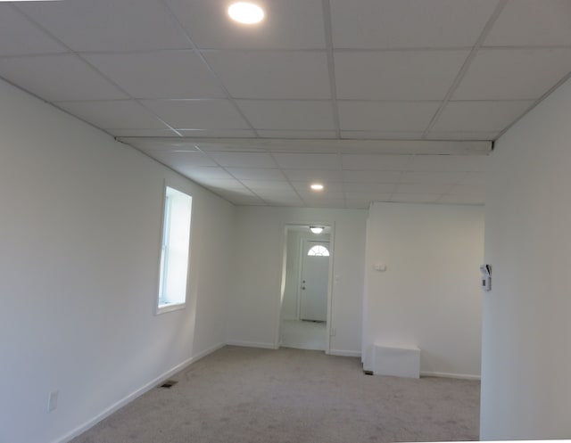 carpeted spare room featuring visible vents, baseboards, and a drop ceiling