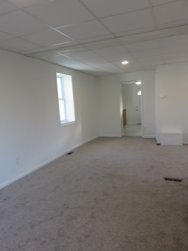 carpeted spare room with baseboards, visible vents, and a drop ceiling