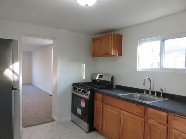 kitchen featuring dark countertops, brown cabinetry, appliances with stainless steel finishes, and a sink