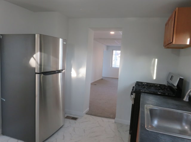 kitchen with visible vents, appliances with stainless steel finishes, brown cabinetry, marble finish floor, and a sink