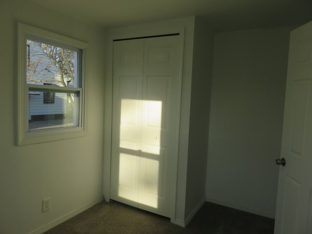 unfurnished room with dark colored carpet and baseboards