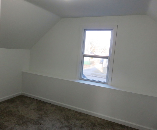 additional living space featuring lofted ceiling, baseboards, and dark carpet