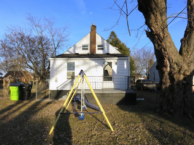 rear view of property with a chimney and a playground