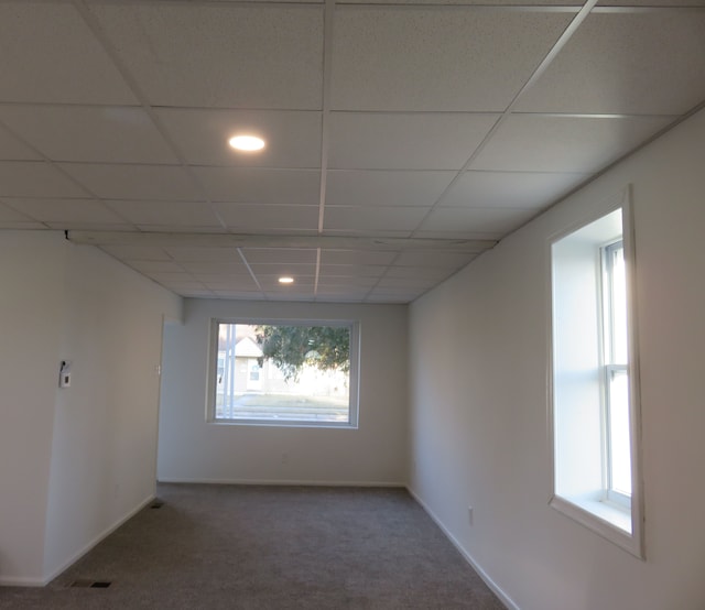 empty room featuring a drop ceiling, baseboards, visible vents, and carpet flooring