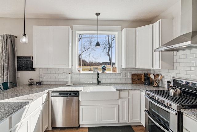 kitchen featuring a sink, backsplash, appliances with stainless steel finishes, and wall chimney exhaust hood