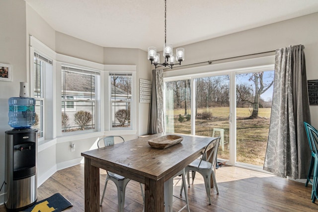 dining space featuring a chandelier, baseboards, and wood finished floors