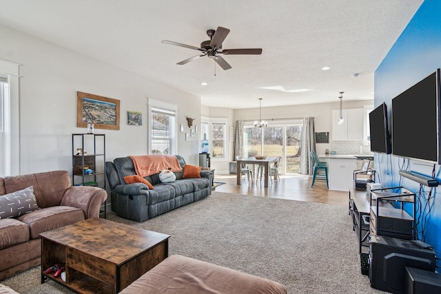 carpeted living room featuring recessed lighting, ceiling fan with notable chandelier, and wood finished floors