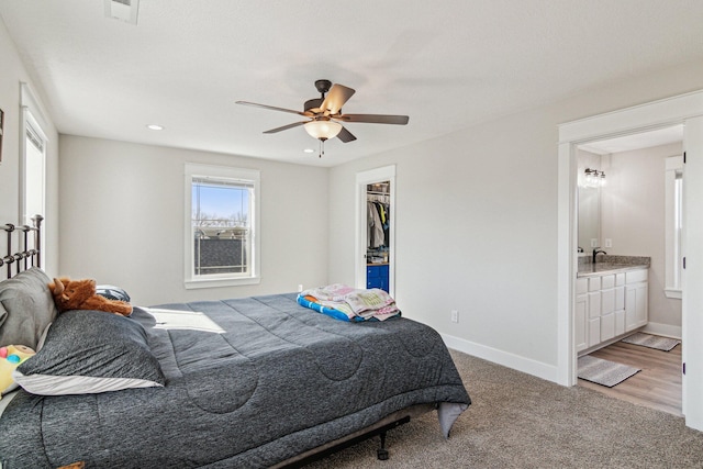 bedroom featuring visible vents, a walk in closet, baseboards, carpet, and ensuite bathroom