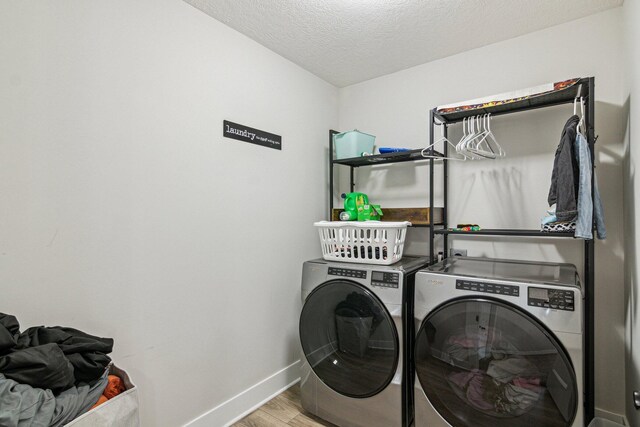 laundry area with light wood-type flooring, independent washer and dryer, a textured ceiling, baseboards, and laundry area