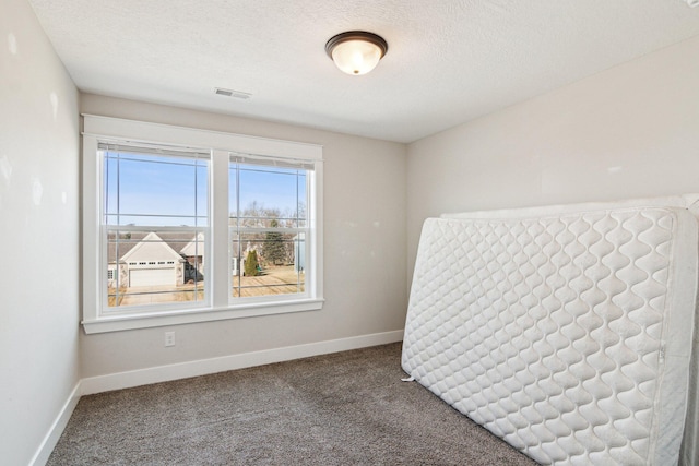 carpeted spare room with visible vents, baseboards, and a textured ceiling