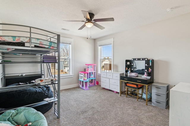 carpeted bedroom with visible vents, a ceiling fan, baseboards, and a textured ceiling