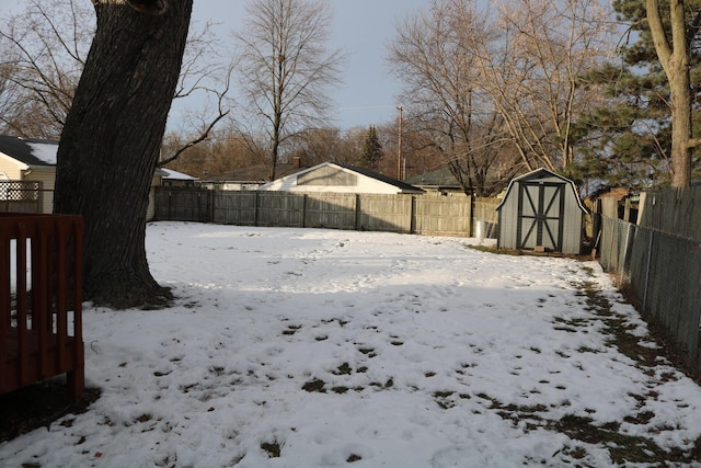 yard layered in snow with a storage shed, an outbuilding, and a fenced backyard