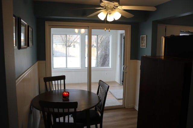 dining room featuring wainscoting, a ceiling fan, and light wood-style floors