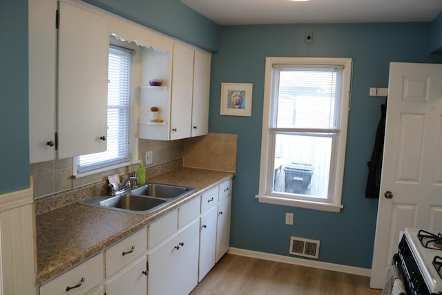 kitchen with white cabinetry, light wood-style floors, visible vents, and a sink