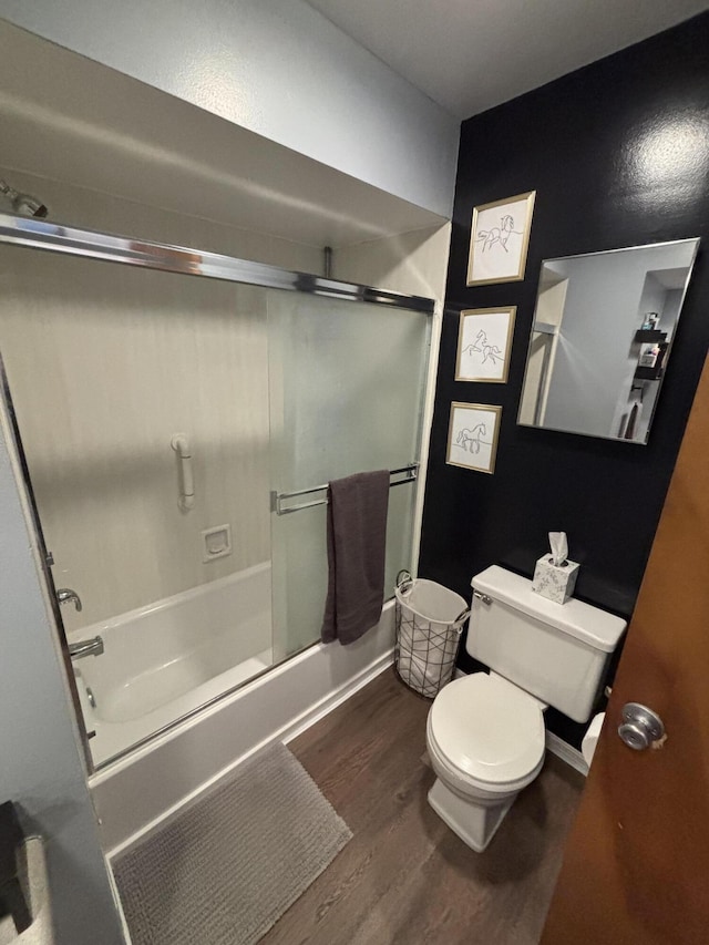 full bath featuring toilet, wood finished floors, and shower / bath combination with glass door