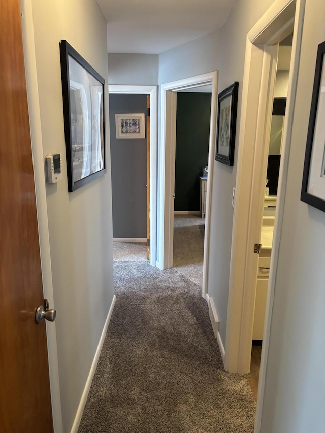 corridor with baseboards and carpet