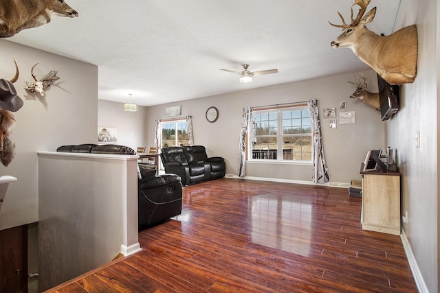 living area featuring ceiling fan, baseboards, and wood finished floors