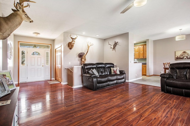 living room with ceiling fan, baseboards, and wood finished floors