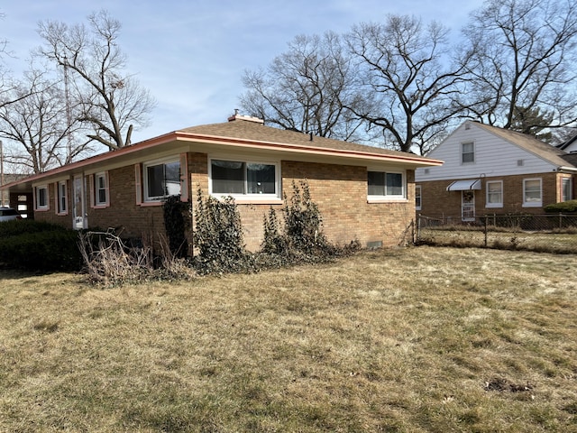 view of side of property featuring a yard, fence, brick siding, and crawl space