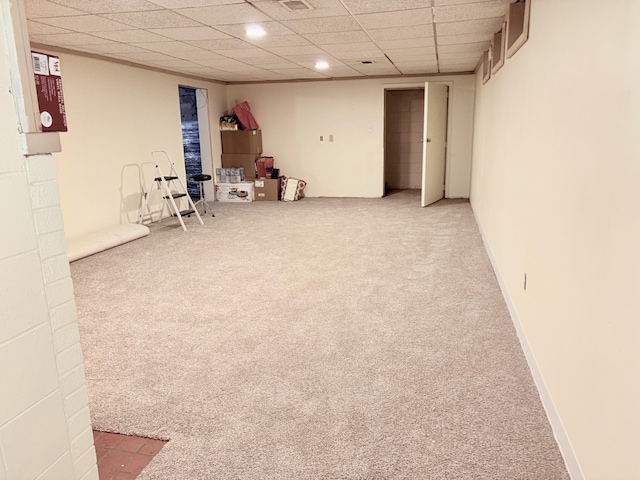 finished basement featuring a drop ceiling, baseboards, and carpet