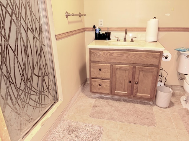 bathroom featuring vanity, a shower with door, toilet, and tile patterned flooring