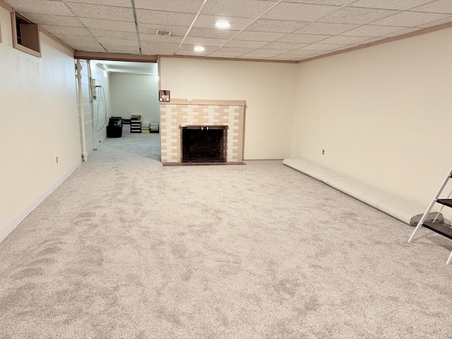 unfurnished living room featuring a drop ceiling, visible vents, a brick fireplace, and carpet