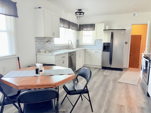 kitchen featuring backsplash, light countertops, light wood-style flooring, white cabinets, and stainless steel appliances