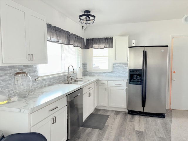 kitchen with light wood-style flooring, a sink, stainless steel appliances, white cabinets, and light countertops