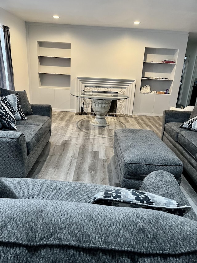 living room with recessed lighting, built in shelves, and wood finished floors