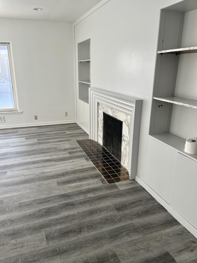 unfurnished living room with a premium fireplace, baseboards, and wood finished floors