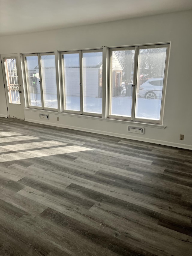 unfurnished room featuring baseboards and dark wood-type flooring