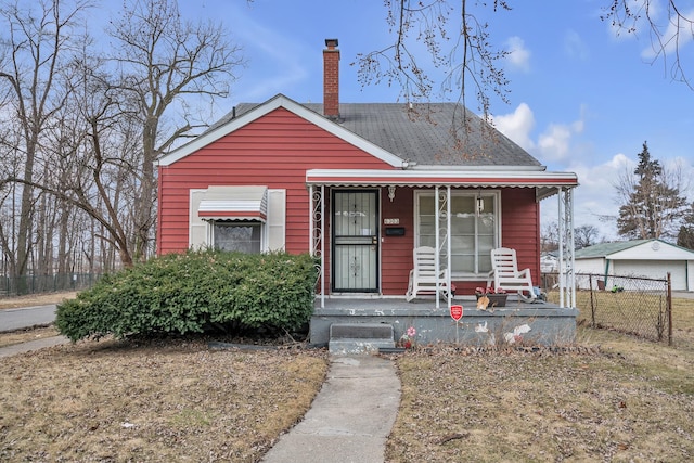 view of front of property featuring covered porch, a chimney, and fence