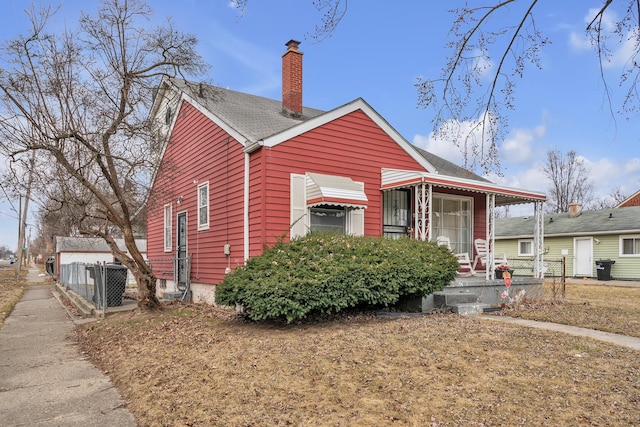 view of front of home featuring a porch, fence, and a chimney