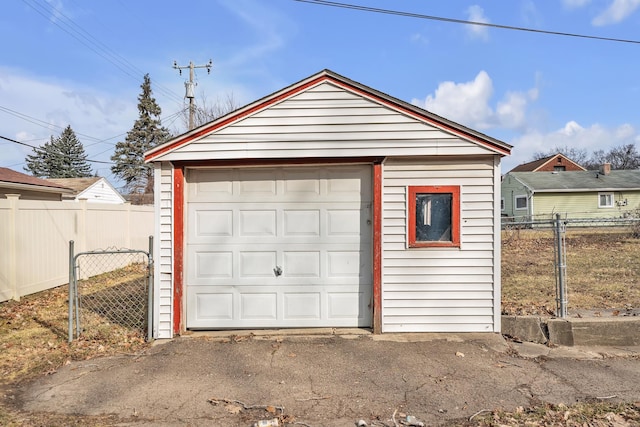 detached garage featuring aphalt driveway and fence