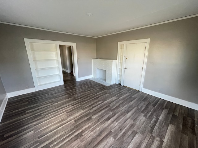 unfurnished living room with baseboards, a brick fireplace, ornamental molding, and dark wood finished floors