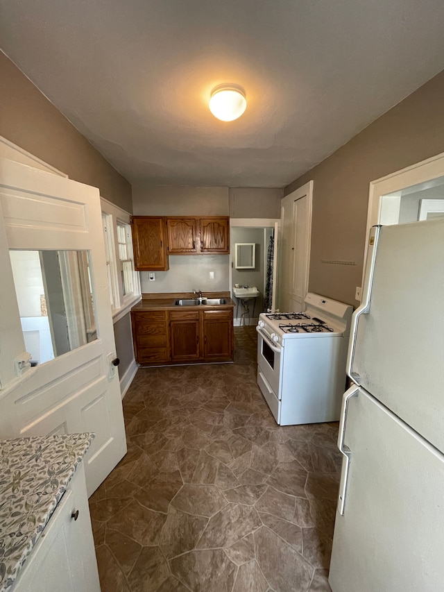 kitchen with brown cabinets, white appliances, light countertops, and a sink