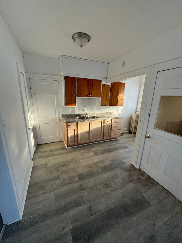 kitchen with a sink, brown cabinets, dark wood-type flooring, and radiator heating unit