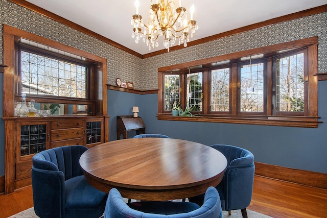 dining room with a chandelier, wallpapered walls, and wood finished floors