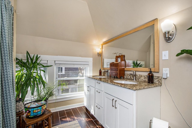 bathroom with double vanity, vaulted ceiling, wood finish floors, and a sink