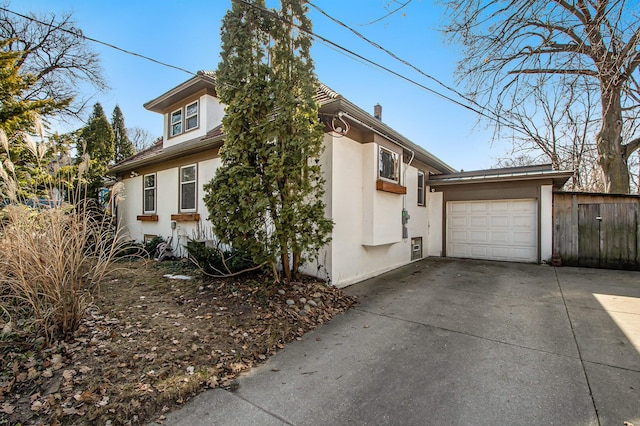 view of side of home featuring concrete driveway, an attached garage, and stucco siding