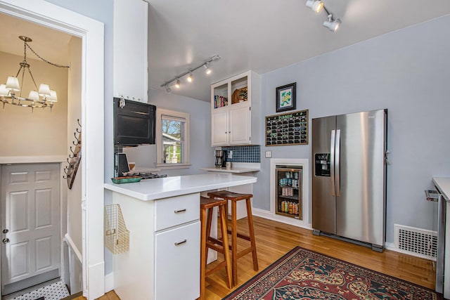 kitchen featuring light wood-type flooring, visible vents, white cabinetry, stainless steel fridge, and light countertops