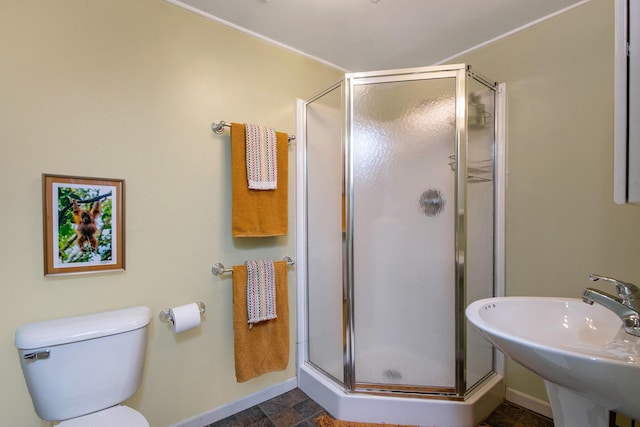 full bath with stone finish floor, a shower stall, baseboards, and a sink